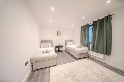 a bedroom with two beds and a couch and a window at Royal Oak Apartments 9 - Free Secure Parking - 2 Bedrooms - Perfect for Contractors in Brentwood