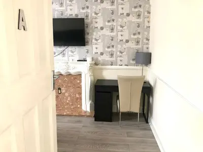 a room with a desk with a television and a table at Ac Lounge 36 Room A in Rochford