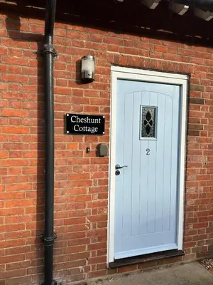 a brick building with a white door and a street sign at Westminster College Cottages, Cambridge in Cambridge