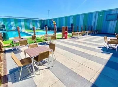 a patio with tables and chairs and a pool at Seawick Holiday Home Horizon 363 in Saint Osyth
