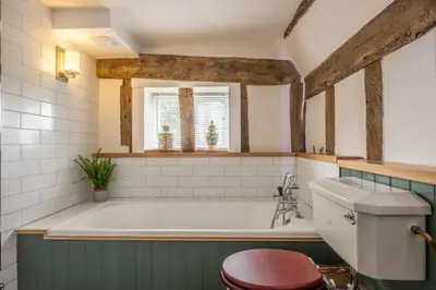 a bathroom with a bath tub and a toilet at Cutbush Farm House in Hingham