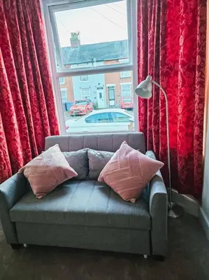 a couch with pillows sitting in front of a window at Spacious House in Ipswich in Ipswich