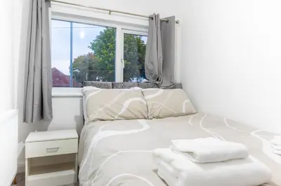 a white bedroom with a bed with towels on it at Southend Retreat KING SUITE Luxury stay with parking in Southend-on-Sea