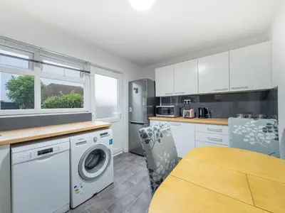 a kitchen with a table and a washing machine in it at Southend Retreat KING SUITE Luxury stay with parking in Southend-on-Sea