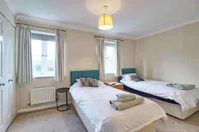 two beds in a room with two windows at By Buildersbeds - Paignton House 4 Bedrooms in Harold Wood