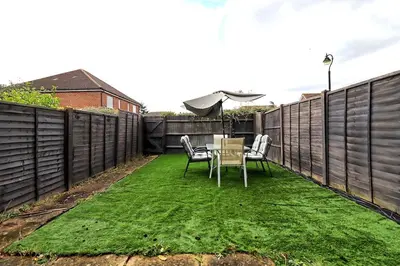 a patio with a table and chairs on the grass at By Buildersbeds - Paignton House 4 Bedrooms in Harold Wood