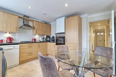 a kitchen with a glass table and chairs at By Buildersbeds - Paignton House 4 Bedrooms in Harold Wood