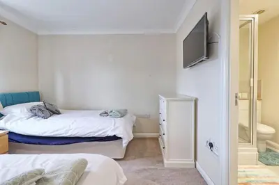 a bedroom with two beds and a television on the wall at By Buildersbeds - Paignton House 4 Bedrooms in Harold Wood