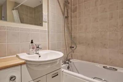 a bathroom with a sink and a bath tub at By Buildersbeds - Paignton House 4 Bedrooms in Harold Wood