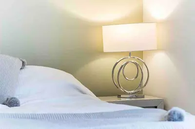 a bedroom with a bed with a lamp on a night stand at By Buildersbeds - Colne House 4 bedrooms in Harold Wood