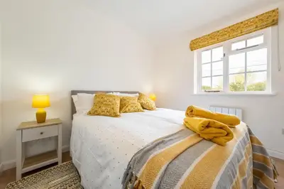 a bedroom with a bed with yellow pillows and a window at The Old Woodstore in Sudbury