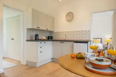 a kitchen with a table with a bowl of fruit on it at The Old Woodstore in Sudbury