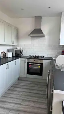 a kitchen with white cabinets and a stove top oven at By Buildersbeds - Heaton House 2 Bedrooms in Havering atte Bower