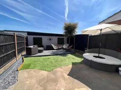a patio with an umbrella and some grass at By Buildersbeds - Heaton House 2 Bedrooms in Havering atte Bower