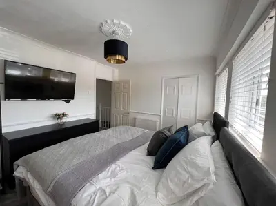 a bedroom with a large bed and a flat screen tv at By Buildersbeds - Heaton House 2 Bedrooms in Havering atte Bower