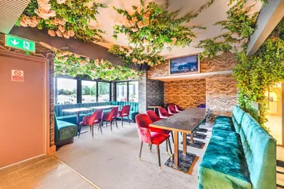a restaurant with a table and red chairs at Palms Hotel & Retreat By Palette London Romford in Hornchurch