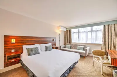 a hotel room with a large bed and a desk at Palms Hotel & Retreat By Palette London Romford in Hornchurch