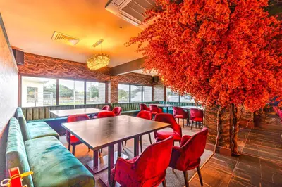 a restaurant with red chairs and a table and a large plant at Palms Hotel & Retreat By Palette London Romford in Hornchurch