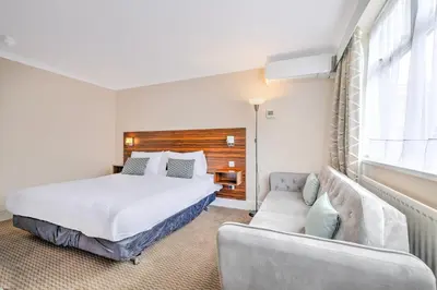 a bedroom with a bed and a couch at Palms Hotel & Retreat By Palette London Romford in Hornchurch