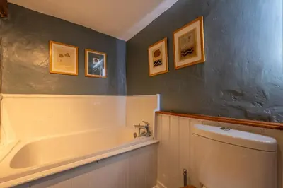a bathroom with a tub and a toilet and pictures on the wall at Cutbush Farm House 6 in Hingham