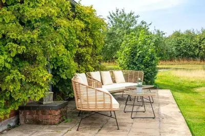a patio with two wicker chairs and a table at Cutbush Farm House 6 in Hingham