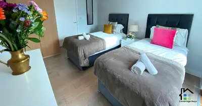 a bedroom with two beds and a vase of flowers at Apartment at Addenbrooke hospital and Bio Campus - Free Private parking in Cambridge