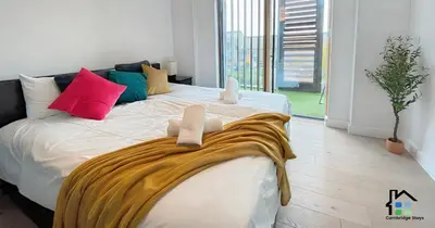 a bedroom with a large white bed with colorful pillows at Apartment at Addenbrooke hospital and Bio Campus - Free Private parking in Cambridge