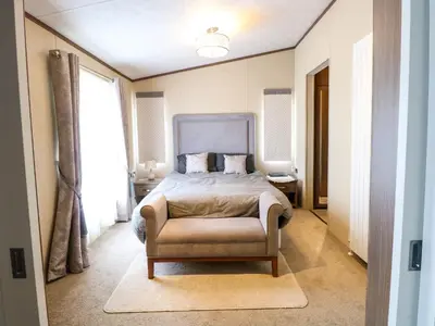 a bedroom with a bed and a chair in it at Lodge 26, Fishing Lakes in Stowmarket
