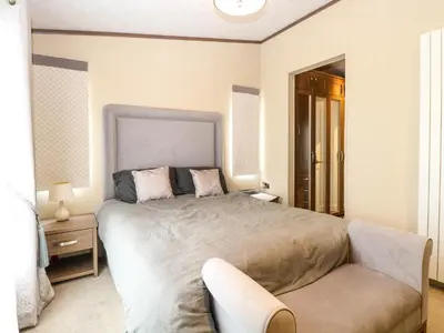 a bedroom with a large bed and a couch at Lodge 26, Fishing Lakes in Stowmarket