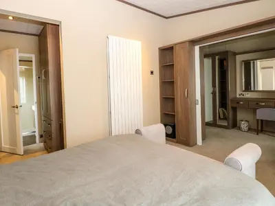 a bedroom with a large bed with two chairs and a desk at Lodge 26, Fishing Lakes in Stowmarket