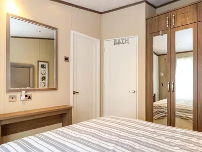 a bedroom with a bed and a mirror at Lodge 26, Fishing Lakes in Stowmarket