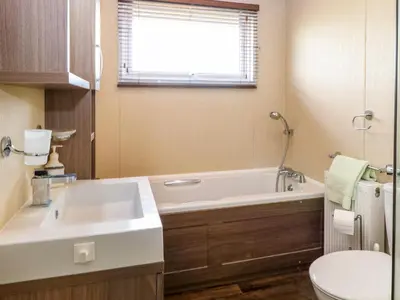 a bathroom with a sink and a tub and a toilet at Lodge 26, Fishing Lakes in Stowmarket