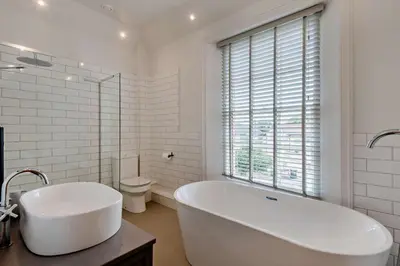 a white bathroom with a tub and a toilet at 5 Bed in Methwold oc-r29770 in Methwold