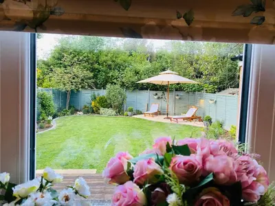 a vase of pink roses sitting on a table next to a yard at Bowershott in Letchworth