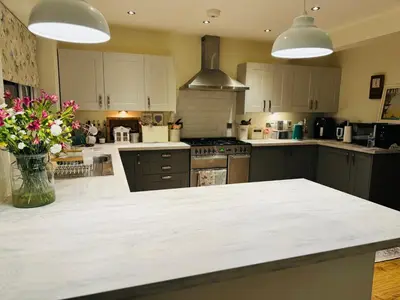 a kitchen with white cabinets and a counter with flowers at Bowershott in Letchworth