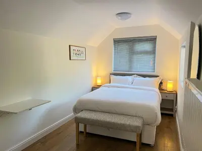 a white bedroom with a bed and a chair at The Cosy Place near centre in Ipswich