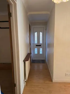 an empty hallway with a door and a wooden floor at Accessible Flat Greater London in Upminster