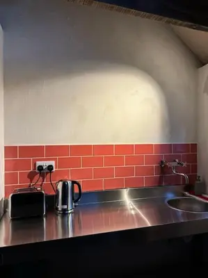 a kitchen counter with a sink and red tiles at Cambridgeshire Wabi-sabi in Barrington