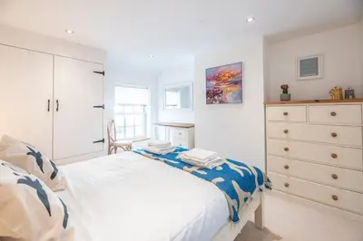 a white bedroom with a bed and a dresser at Beachcomber, Aldeburgh in Aldeburgh
