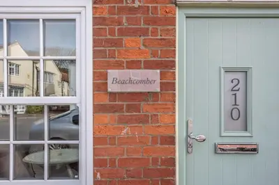 a door to a brick building with a sign on it at Beachcomber, Aldeburgh in Aldeburgh