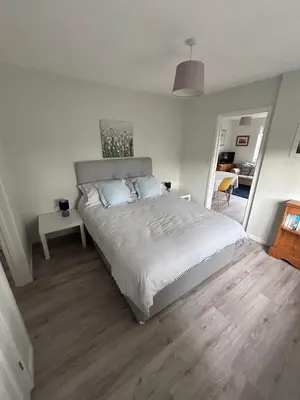 a bedroom with a large bed with a wooden floor at Hamble House Holiday Let in Woodbridge