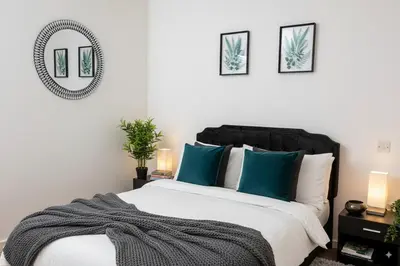 a bedroom with a bed with blue pillows and a mirror at The Falcon's Nest - Central in Bury Saint Edmunds