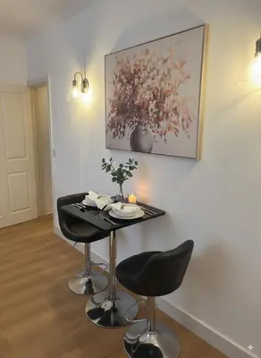 a table with two chairs and a painting on the wall at The Falcon's Nest - Central in Bury Saint Edmunds
