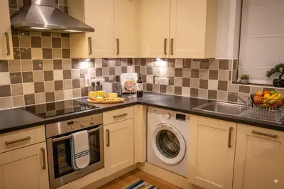 a kitchen with a sink and a washing machine at The Falcon's Nest - Central in Bury Saint Edmunds