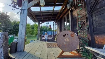 a woman standing on a porch of a house at Little Lodge Glamping in Halesworth