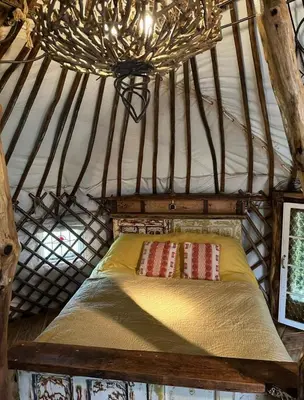 a bed in a yurt with a chandelier at Little Lodge Glamping in Halesworth