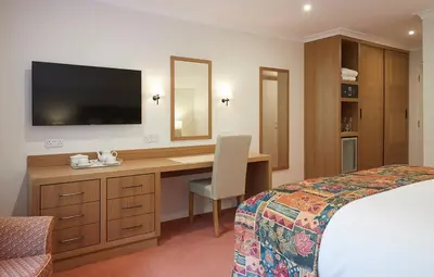 a hotel room with a desk with a television and a bed at Arundel House Hotel in Cambridge