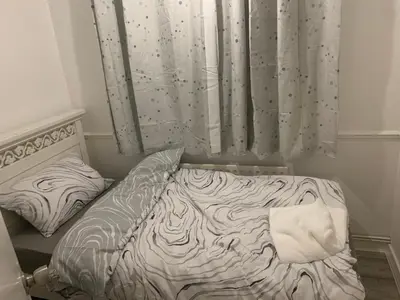 a bed in a room with a curtain and a crib at At Apex House single room in Horndon on the Hill