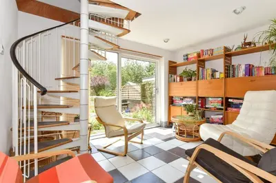 a living room with a spiral staircase and chairs at Scandi inspired holiday home Brentwood in Brentwood