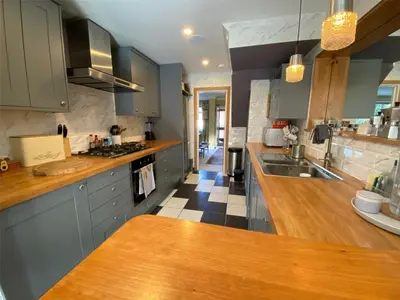a kitchen with blue cabinets and a wooden counter top at Scandi inspired holiday home Brentwood in Brentwood